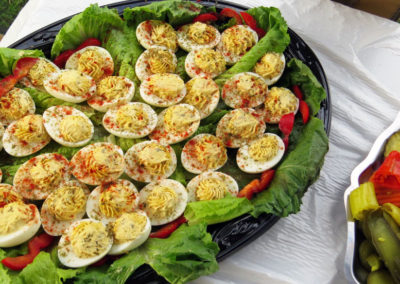 Deviled eggs on a bed of lettuce and red peppers, sprinkled with paprika